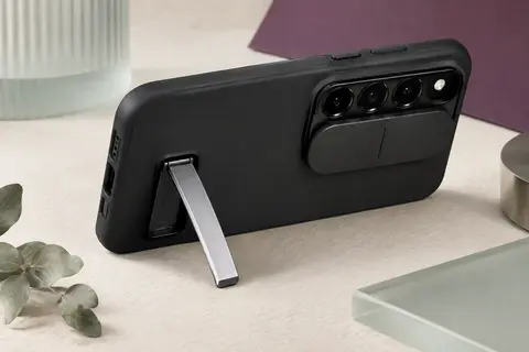 Coque noire mate pour Galaxy S26 avec cache caméra rabattable et support métallique déployé.