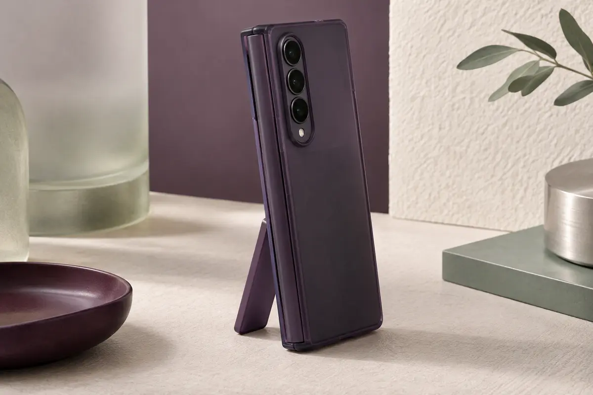 Smartphone pliable au format livre fermé dans une coque violet foncé, debout sur sa béquille déployée, charnière protégée sur le grand côté