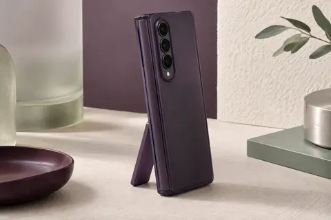 Smartphone pliable au format livre fermé dans une coque violet foncé, debout sur sa béquille déployée, charnière protégée sur le grand côté